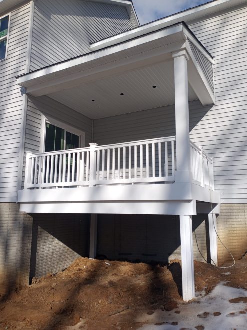 A Backyard porch with white vinyl railing and posts