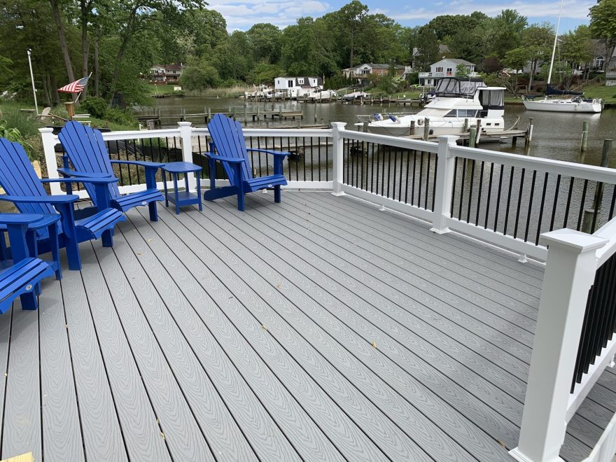 A riverfont deck with Trex Select Pebble Gray Composite deck boards with white vinyl railing with black aluminum baluters