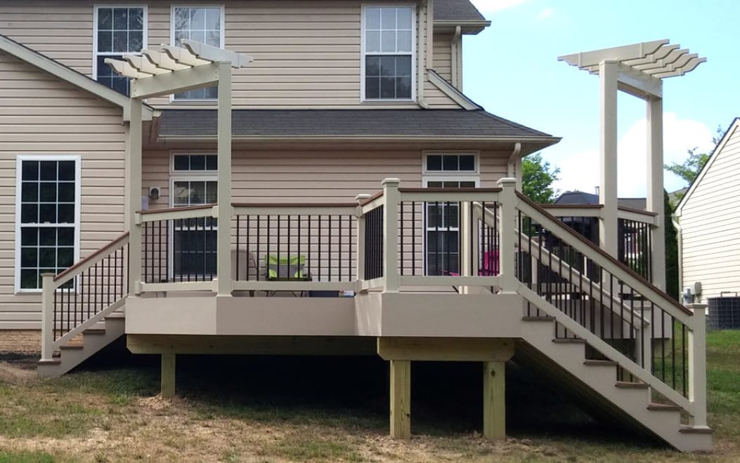 Composite Deck with tan vinyl railing with matching cocktail rail and black ballusters and 2 tan pergolas