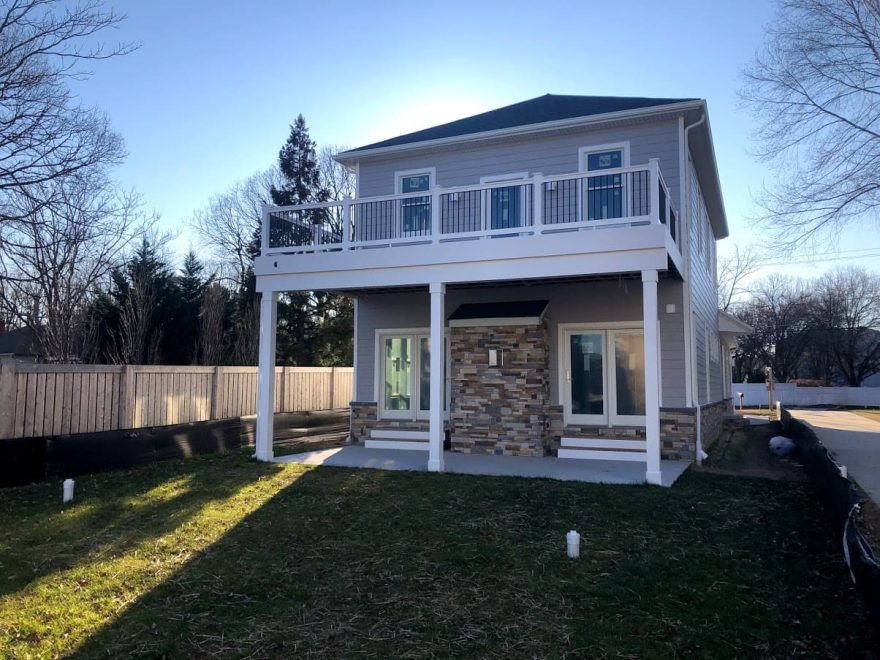 Deck with White Washington Vinyl Railing + Black Aluminum Balusters + Deck Drain and gutters to keep the space below the deck dry in Arnold MD